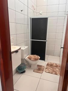 a bathroom with a toilet and a shower with rugs at Casa completa para ate 10 pessoas in Campo Novo do Parecis