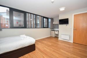 ein Schlafzimmer mit einem Bett und einem TV sowie einige Fenster in der Unterkunft Convenient Budget Studio in Central Sheffield in Midland