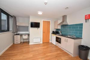 eine Küche mit weißen Schränken und blauen Fliesen in der Unterkunft Convenient Budget Studio in Central Sheffield in Midland
