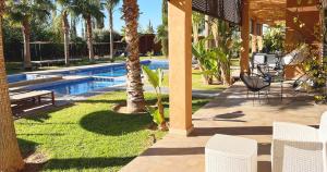 Una piscina con palmeras y sillas al lado de una casa. en Maison d'Hotes Oasis Marrakech Route dOuarzazate, en Oulad Akkou