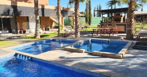 una piscina frente a un edificio con palmeras en Maison d'Hotes Oasis Marrakech Route dOuarzazate, en Oulad Akkou