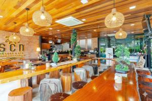 Suchanan Resort Rayong في بان تشانغ: مطعم بطاولات وكراسي خشبية واضاءات قلادة