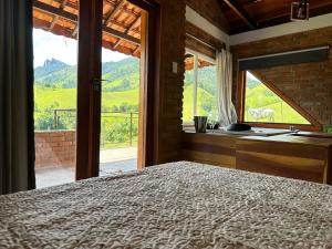 ein Schlafzimmer mit einem Bett und einem Fenster mit Aussicht in der Unterkunft Chalés das Cachoeiras - Amor Perfeito in Resende
