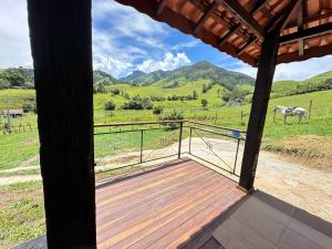 eine Veranda mit Blick auf ein Pferd auf einem Feld in der Unterkunft Chalés das Cachoeiras - Amor Perfeito in Resende