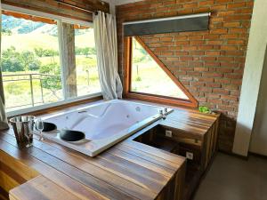 eine große Badewanne in einem Raum mit Fenster in der Unterkunft Chalés das Cachoeiras - Amor Perfeito in Resende