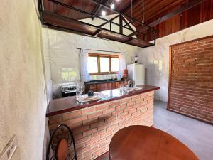 eine Küche mit einer Backsteintheke und einem Holztisch in der Unterkunft Chalés das Cachoeiras - Amor Perfeito in Resende + 16 Fotos