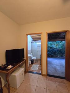 a living room with a flat screen tv and a table at Pousada Rancho Minêro in Delfinópolis