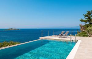 una piscina con due sedie e l'oceano di The Stone House a Oziás Altre 15 foto