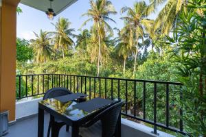 a balcony with a table and chairs and palm trees at La Sky Stay in Ukulhas