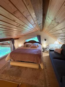 a bed in the middle of a room with a couch at La cabane sur l'étang in Étival-Clairefontaine