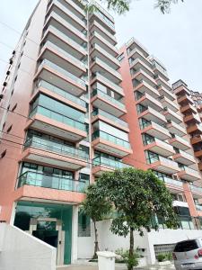a tall building with a tree in front of it at Lar e Mar PG in Praia Grande