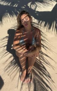 una mujer en bikini sentada en la playa en Punta Cana Aruba Beach Apartcomplex 1, en Punta Cana