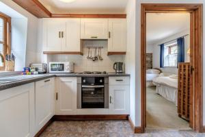 eine Küche mit weißen Schränken und einem Herd in der Unterkunft 3 Bed in Knighton oc-b29329 in Felindre