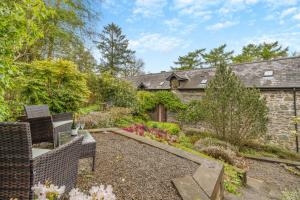 ein Garten mit Stühlen und ein Steinhaus in der Unterkunft 2 Bed in Knighton oc-t29330 in Felindre