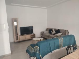 a living room with a couch and a tv at Studio en rez de jardin in Hammamet