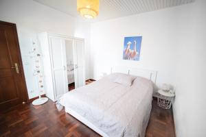 Un dormitorio con una cama blanca y suelo de madera. en Ferienhaus Treibholz, en Funchal