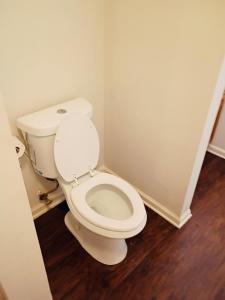 a white toilet in a bathroom with wooden floors at Fletcher Street Hideaway Room 8 with Cozy Vibes in Atlanta