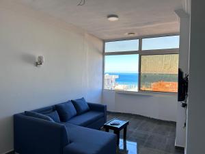 a living room with a blue couch and a large window at Ewa in Hurghada