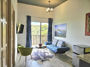 Jardin De Poas Hotel & Nature Resort في Poás: غرفة معيشة مع أريكة زرقاء وشرفة