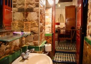 a bathroom with a sink and a stone wall at Riad Dar Iman in Fès