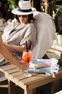 a woman in a hat sitting at a table with a drink at Ayla Corfu in Kavos