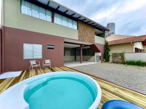 a hot tub on a wooden deck in front of a house at Casa Completa com Piscina Churrasqueira Wi-Fi a 300m da Praia Acomoda 10 Pessoas, 3 Quartos com Ar-Condicionado in Penha