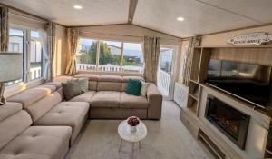 Sea View Chalet Steps from Durdle Door Sleeps 6 في ويست لولوورث: غرفة معيشة مع أريكة وتلفزيون