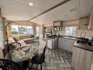 Sea View Chalet Steps from Durdle Door Sleeps 6 في ويست لولوورث: مطبخ وغرفة معيشة مع طاولة وكراسي