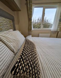 Sea View Chalet Steps from Durdle Door Sleeps 6 في ويست لولوورث: سرير في غرفة نوم ذات نافذة كبيرة