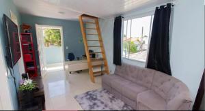 ein Wohnzimmer mit einer Couch und einem Fenster in der Unterkunft Casa em floripa in Florianópolis