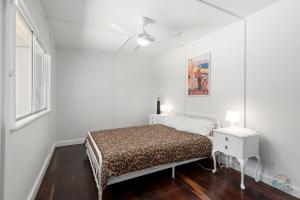 a white bedroom with a bed and a ceiling fan at Playgrounds in Lancelin