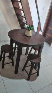 un tavolo di legno e due sgabelli con una pianta sopra di Chalé Borboletas Centro Pipa RN a Pipa Altre 6 foto