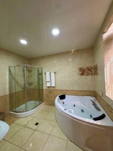 a bathroom with a tub and a shower and a sink at Cosmos Hotel in Yakkasaray +2 photos