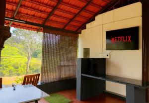 um quarto com uma televisão na parede e uma mesa em Rafters Retreat Coorg - The Riverside Homestay em Srimangala
