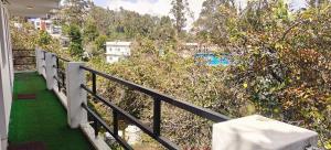 a balcony with a railing and green grass and trees at KSR Aura Homestay in Kodaikānāl