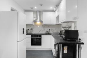 a kitchen with white cabinets and a microwave at 2 Bedroom house,BrownhillRd SE6 in London +3 photos