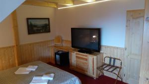 a room with a tv and a bed and a table at Penzion U Pacošů in Malenovice