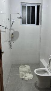 een witte badkamer met een toilet en een raam bij Malindi Modern 2BR Apartment in Malindi