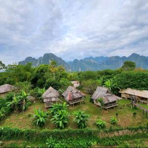 a group of huts with mountains in the background at Queens hotel in Vang Vieng