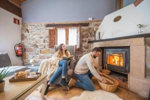 a man and woman sitting in a living room with a fireplace at Carbayu Senda del Oso in Proaza