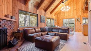 a living room with a leather couch and a fireplace at 5BDR Hot Tub Deck Firepit Mins to Village Lake The Hilltop by AvantStay in North Shore