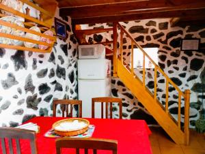 a dining room with a table and a refrigerator at Adega Velha in Calheta de Nesquim