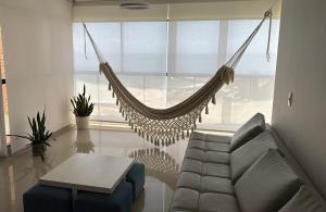 a hammock in a living room with a couch and a table at Oceanfront Playa Grande 10 min Airport Maiquetia Aeropuerto in Maiquetía
