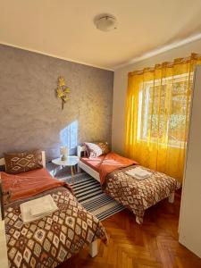 a bedroom with two beds and a table and a window at Red House Apartment in Kotor