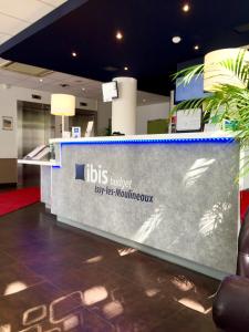 a reception desk in a building with a sign at ibis budget Issy Les Moulineaux Paris Ouest in Issy-les-Moulineaux