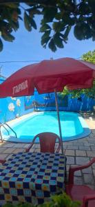 Pousada Recanto do Cajueiro في ساو جوزيه دا كوروا غراندي: مظلة وطاولة وكراسي أمام حوض السباحة
