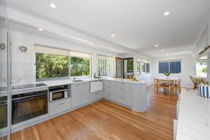 a kitchen with white cabinets and windows and a table at Noosa Escape 2BR Ocean Views, Walk to Beach in Noosa Heads