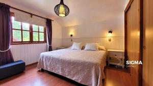 um quarto com uma cama com lençóis brancos e uma janela em Amplia Casa Familiar en Condominio Privado em Pucón