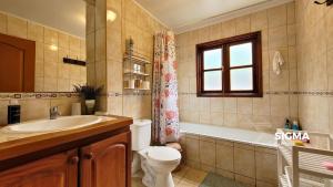 um banheiro com vaso sanitário, banheira e pia em Amplia Casa Familiar en Condominio Privado em Pucón