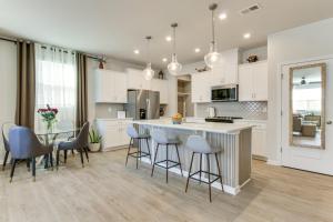 3 Mi to Lake Wylie! Modern Charlotte Townhome في Pine Harbor: مطبخ مع خزائن بيضاء وطاولة وكراسي